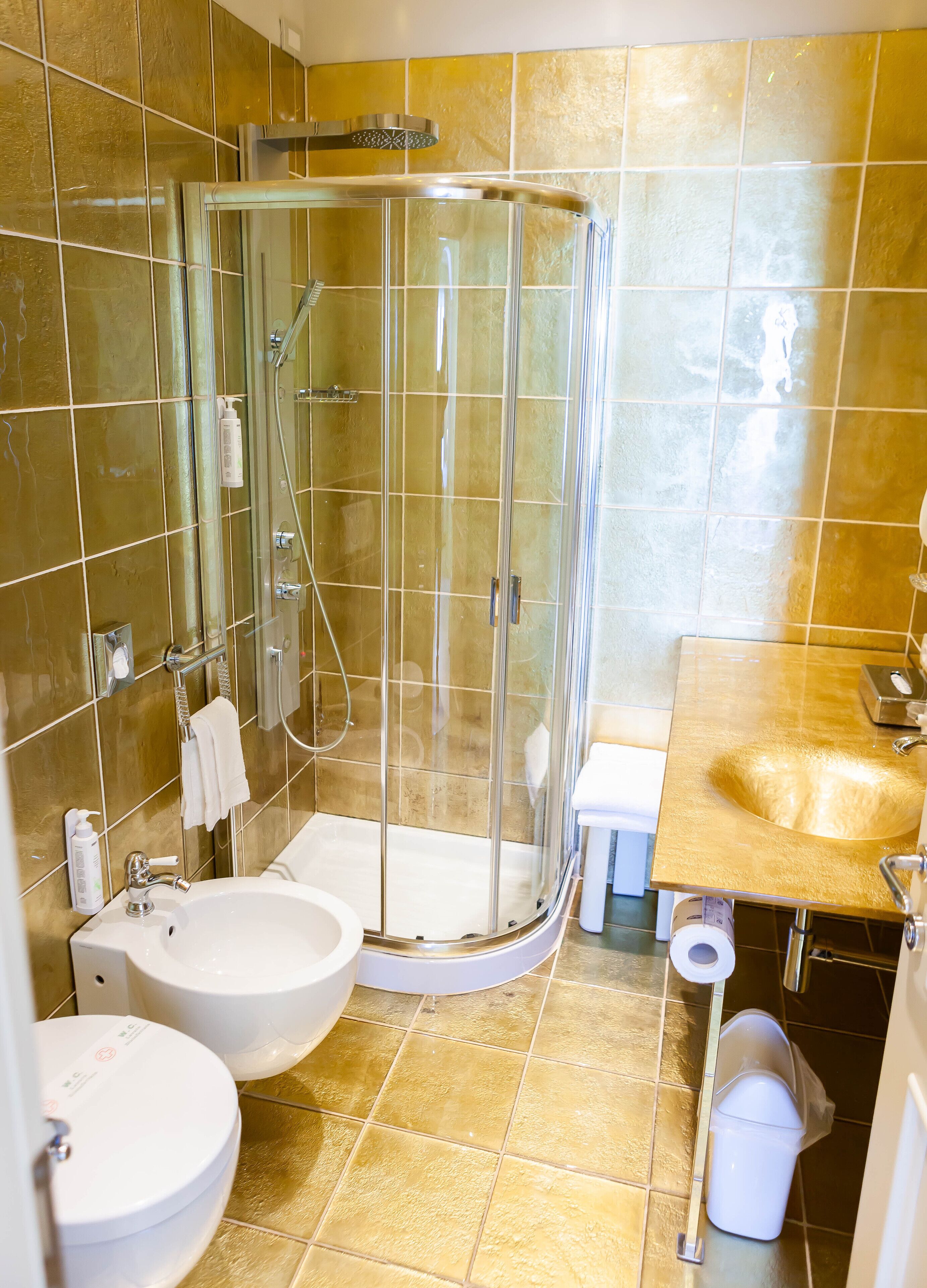 A modern bathroom with a glass-enclosed shower, two sinks, and a toilet.