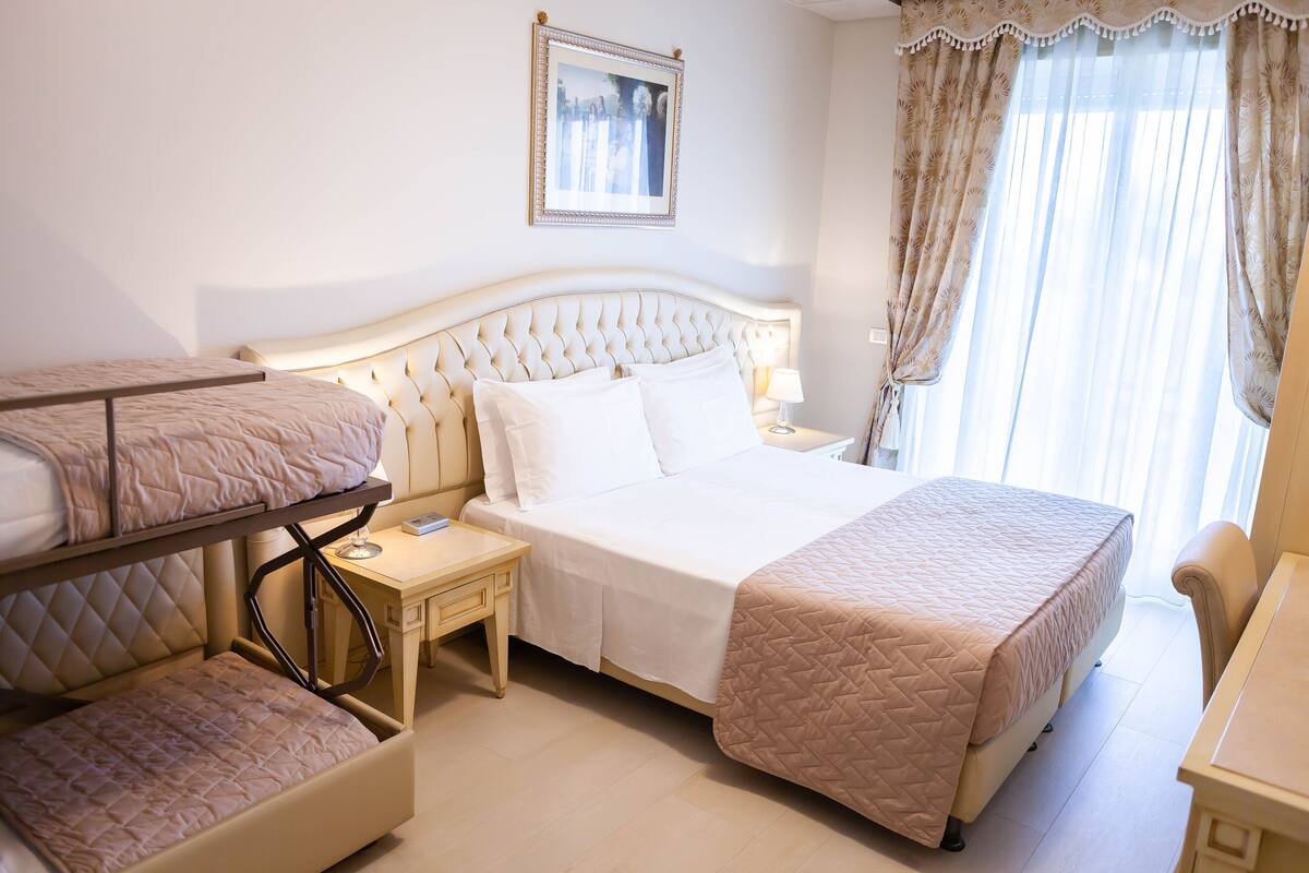 A hotel room with a queen-sized bed, a smaller bed, a desk, and a chair.