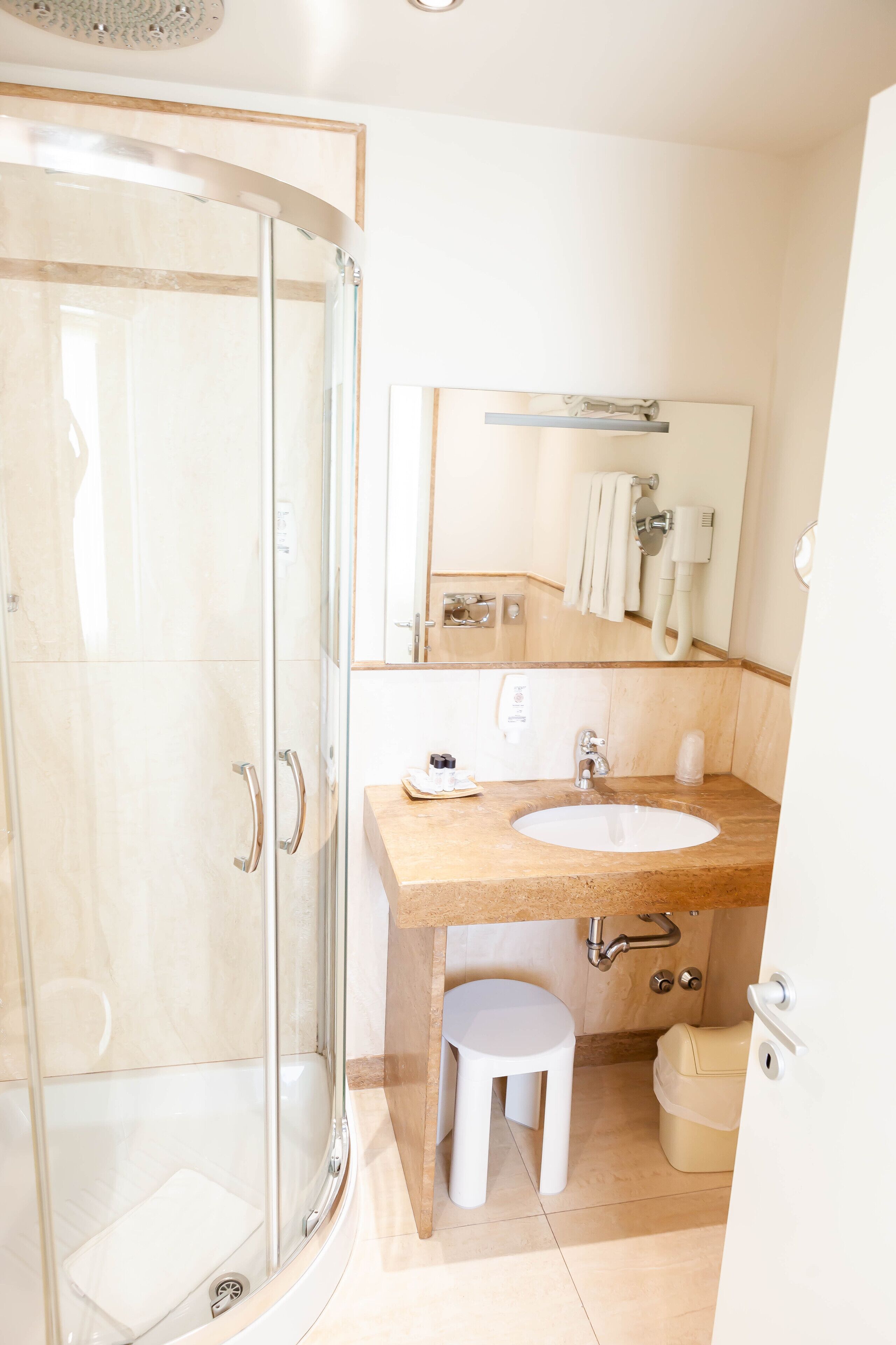 Un baño moderno con ducha de vidrio, lavamanos con toallero y inodoro.