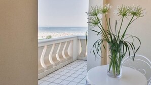 A balcony with a view of the beach, a white table, and a vase with flowers. - Hotel Conchiglia (Cervia)