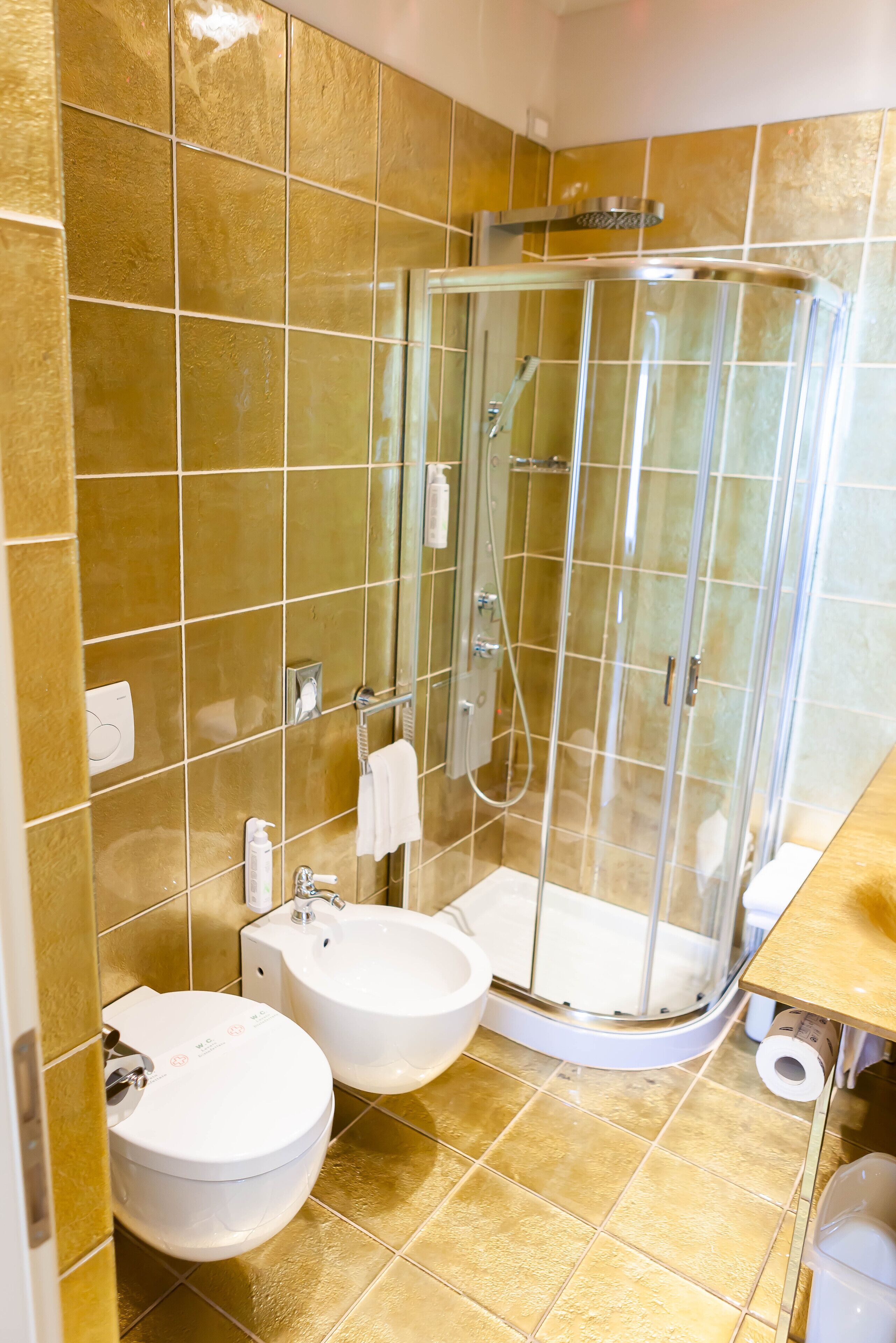 A bathroom with a glass-enclosed shower, two sinks, and a toilet.
