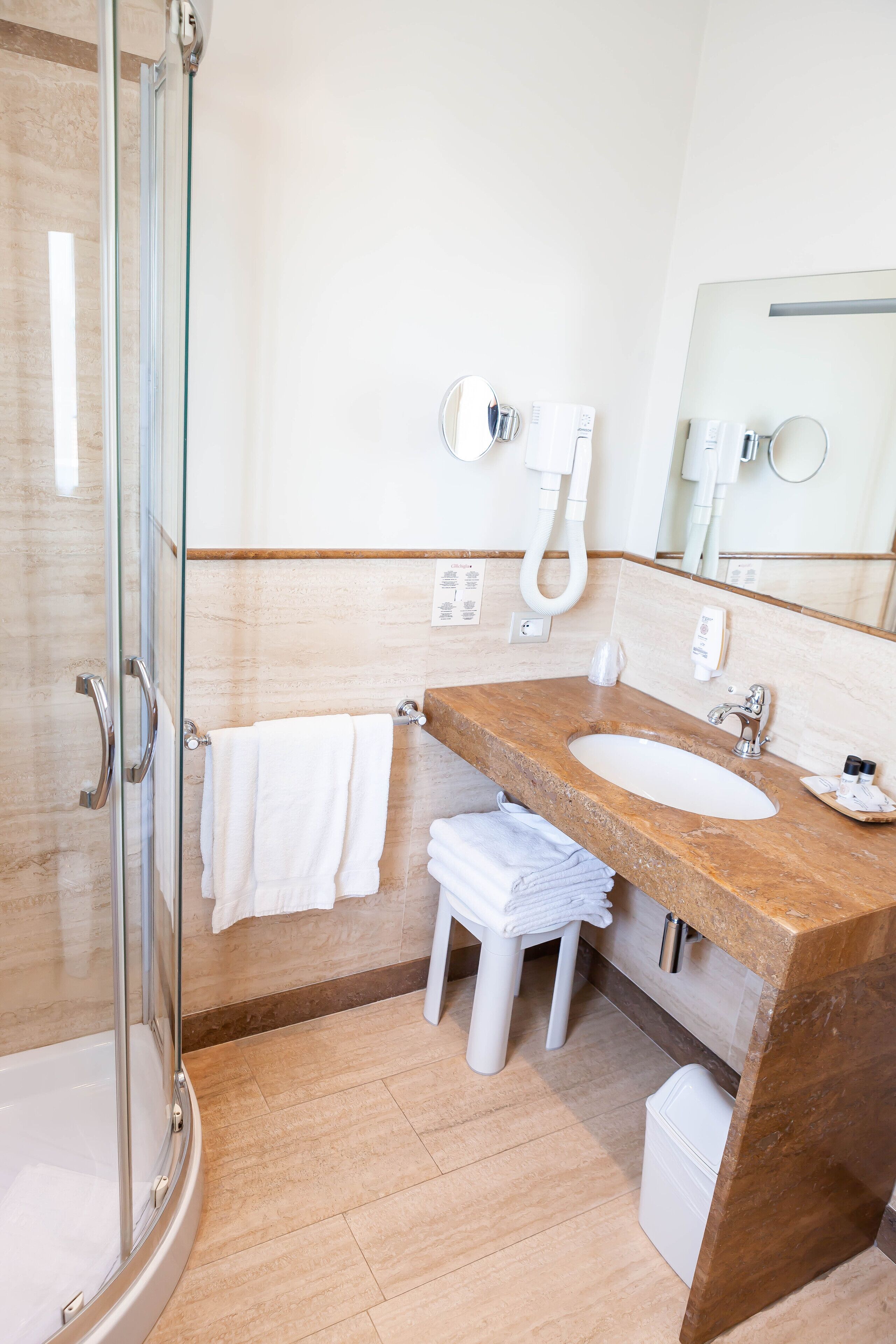 A modern bathroom with a glass-enclosed shower, a marble sink, and a large mirror.
