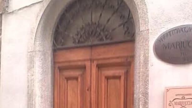 A double wooden door with a plaque above it.