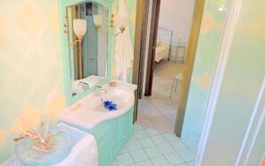 A bathroom with a turquoise vanity, a white sink, and a mirror. - Bounganville PT (Budoni)