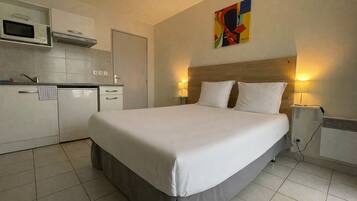 Una habitación de hotel con cama, kitchenette y un cuadro en la pared.