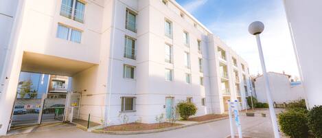 A modern building with a gated entrance, multiple windows, and a clear sky.