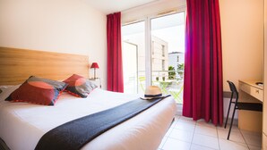 Une chambre d’hôtel avec un lit, un bureau et une vue sur l’extérieur.