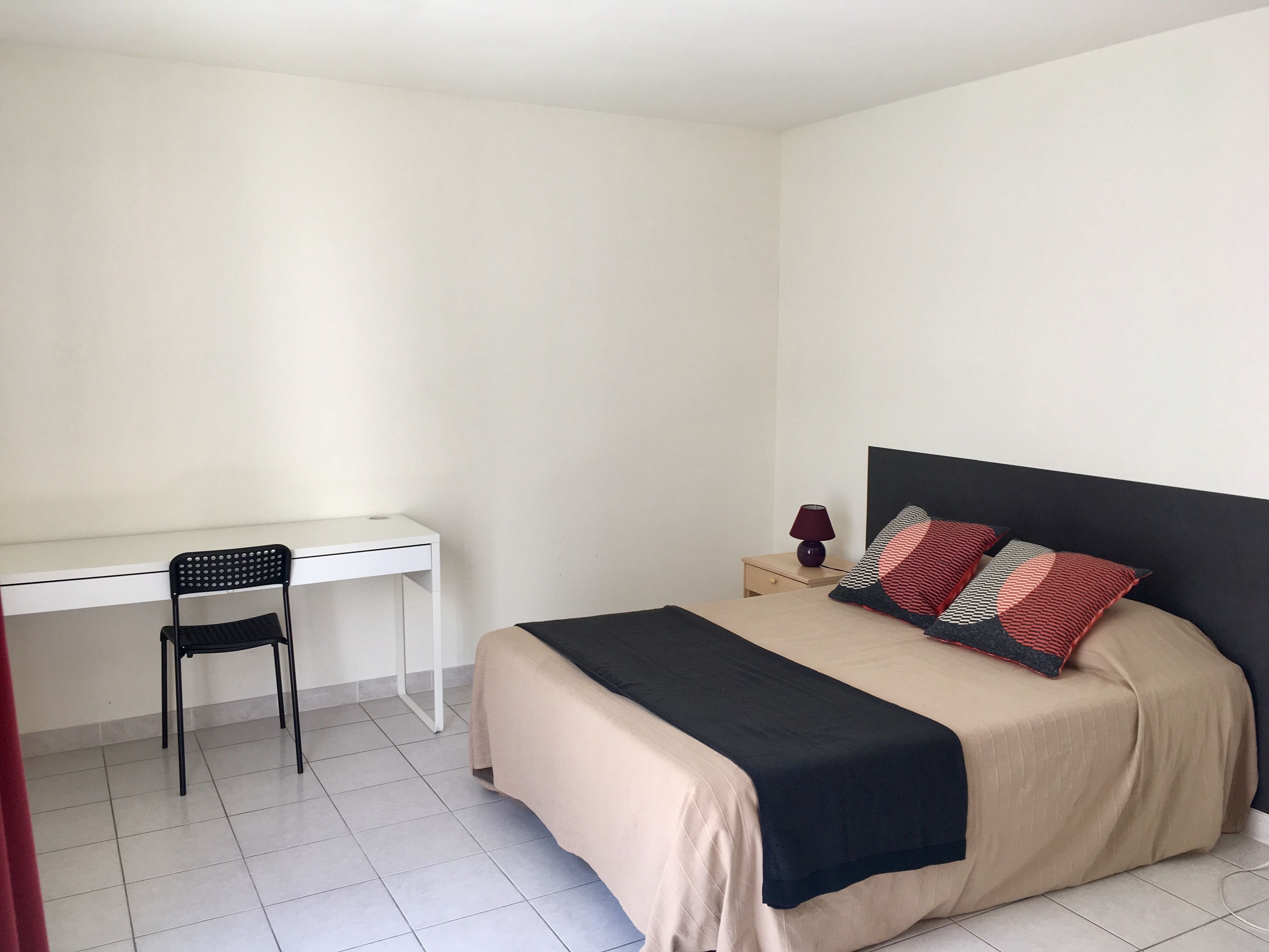 A bedroom with a bed, a desk, and a chair.