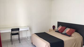 A bedroom with a bed, a desk, and a chair.