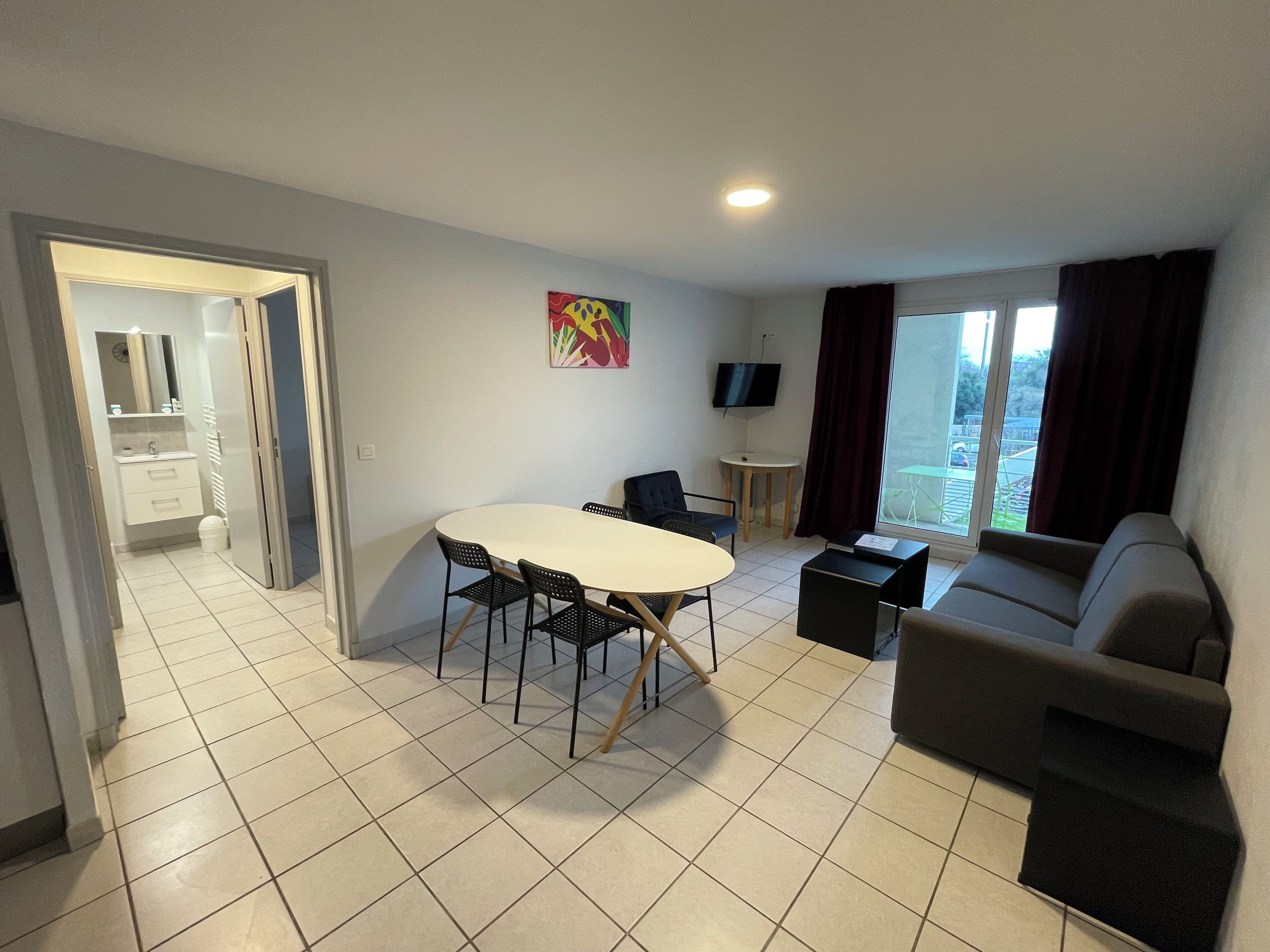 A modern living room with a dining table, sofa, and a TV.