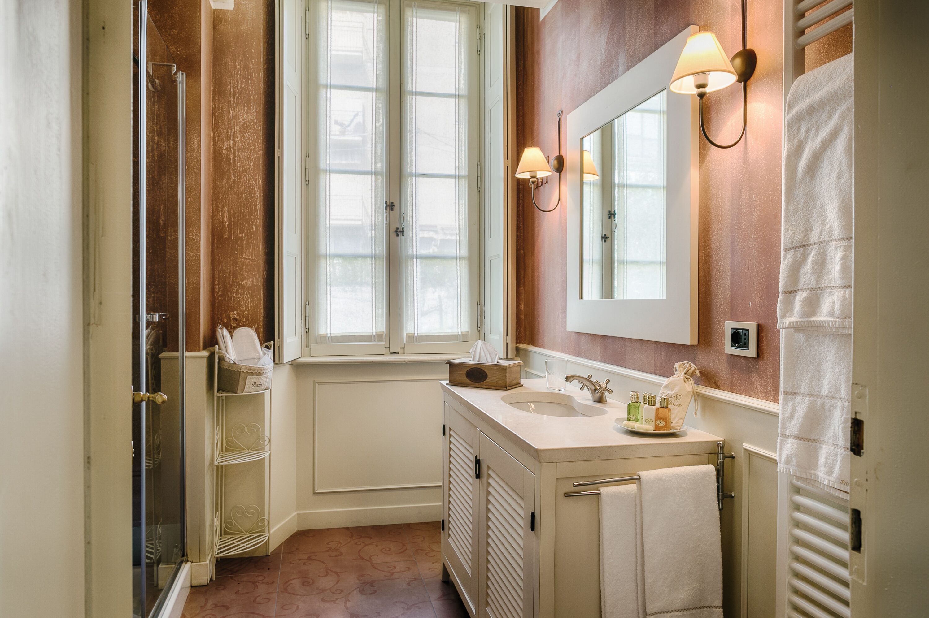 A bathroom with a large window, a sink with a mirror, and a towel rack.