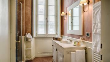 A bathroom with a large window, a sink with a mirror, and a towel rack.
