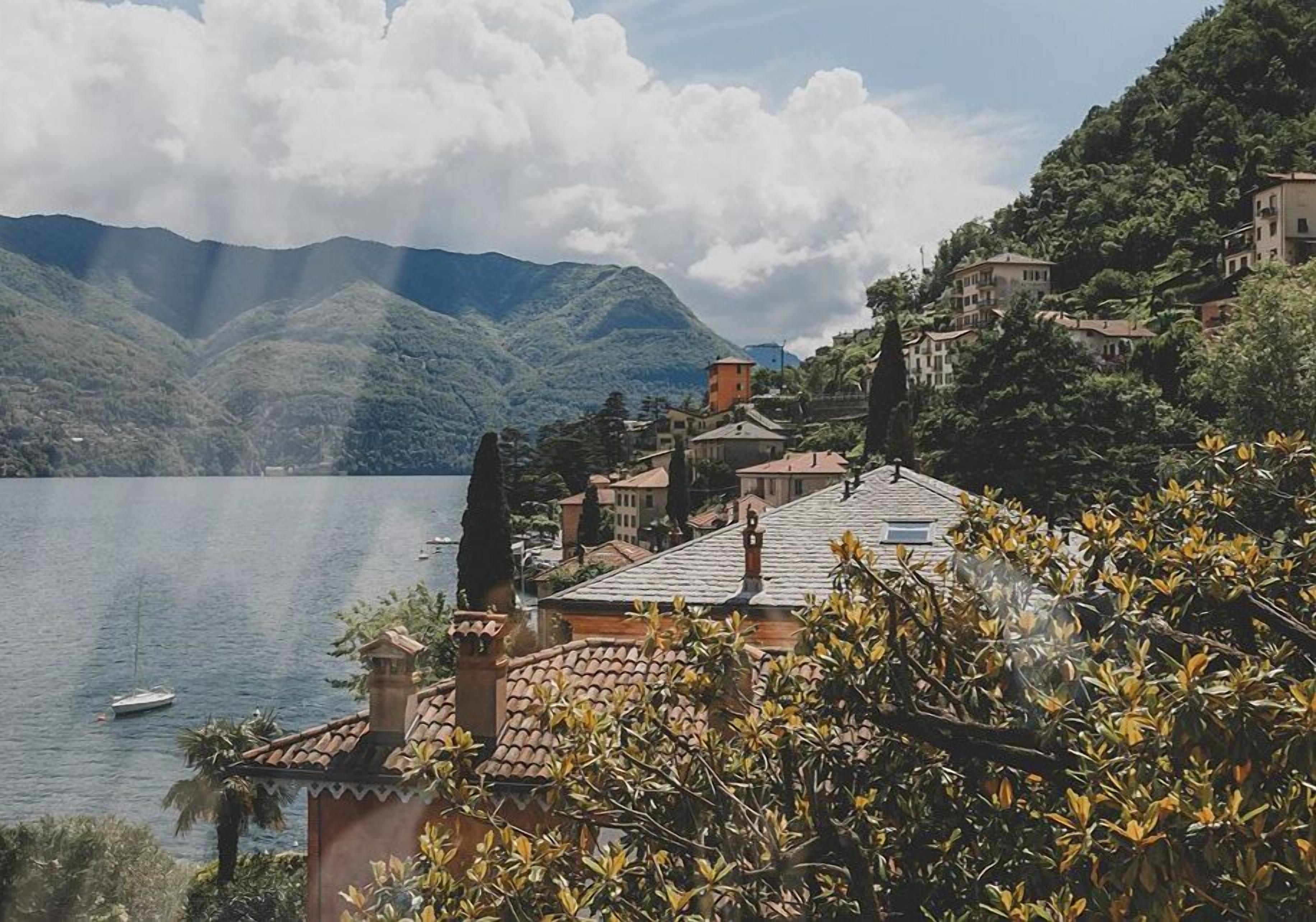 A coastal village with terraced houses, a lake, and mountains in the background.