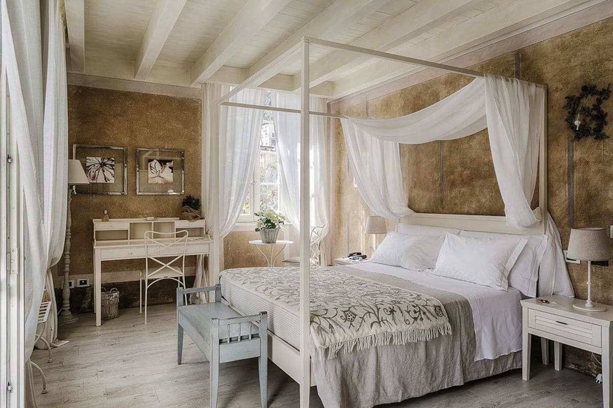 A bedroom with a four-poster bed, a desk, and a chair.