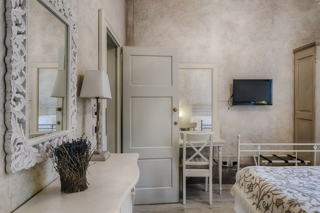 Une chambre à coucher avec un lit, un bureau, une chaise, un téléviseur et une porte.