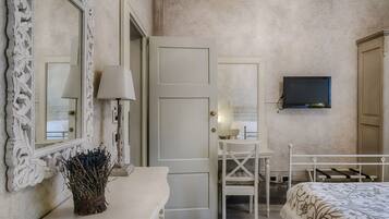 Une chambre à coucher avec un lit, un bureau, une chaise, un téléviseur et une porte.