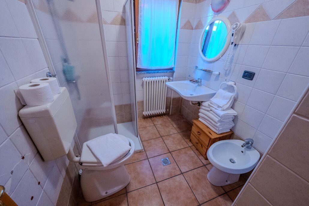 A bathroom with a toilet, shower, sink, and a mirror.