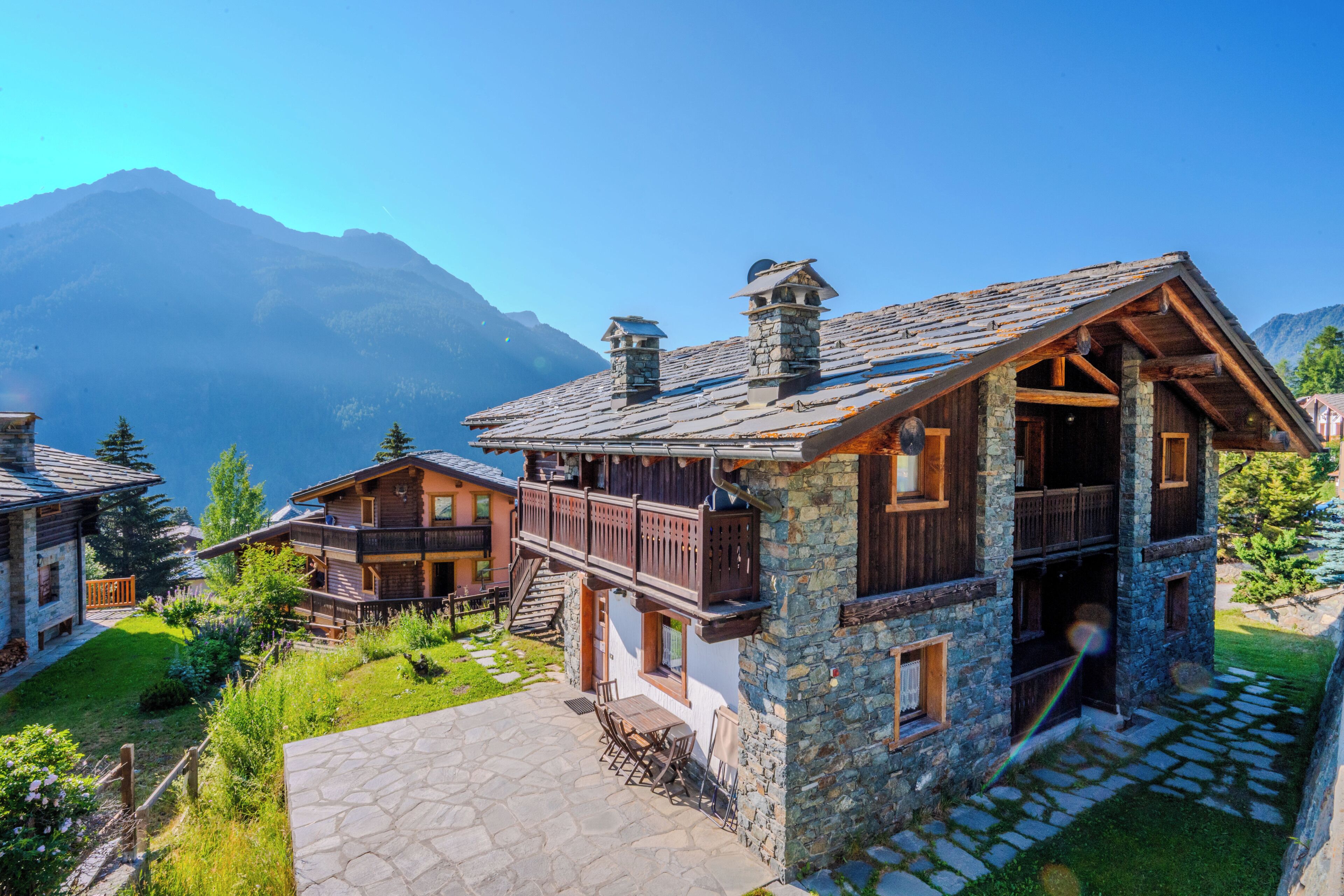 Un rifugio di montagna con facciata in pietra, balconi in legno e una scalinata in pietra che conduce all'ingresso.