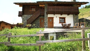 Un edificio de estilo chalé con fachada de piedra, balcones de madera y una chimenea de piedra.
