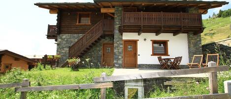 A chalet-style building with a stone facade, wooden balconies, and a stone chimney.