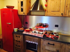 Una cocina con armarios de madera, un refrigerador rojo y una campana extractora de acero inoxidable.
