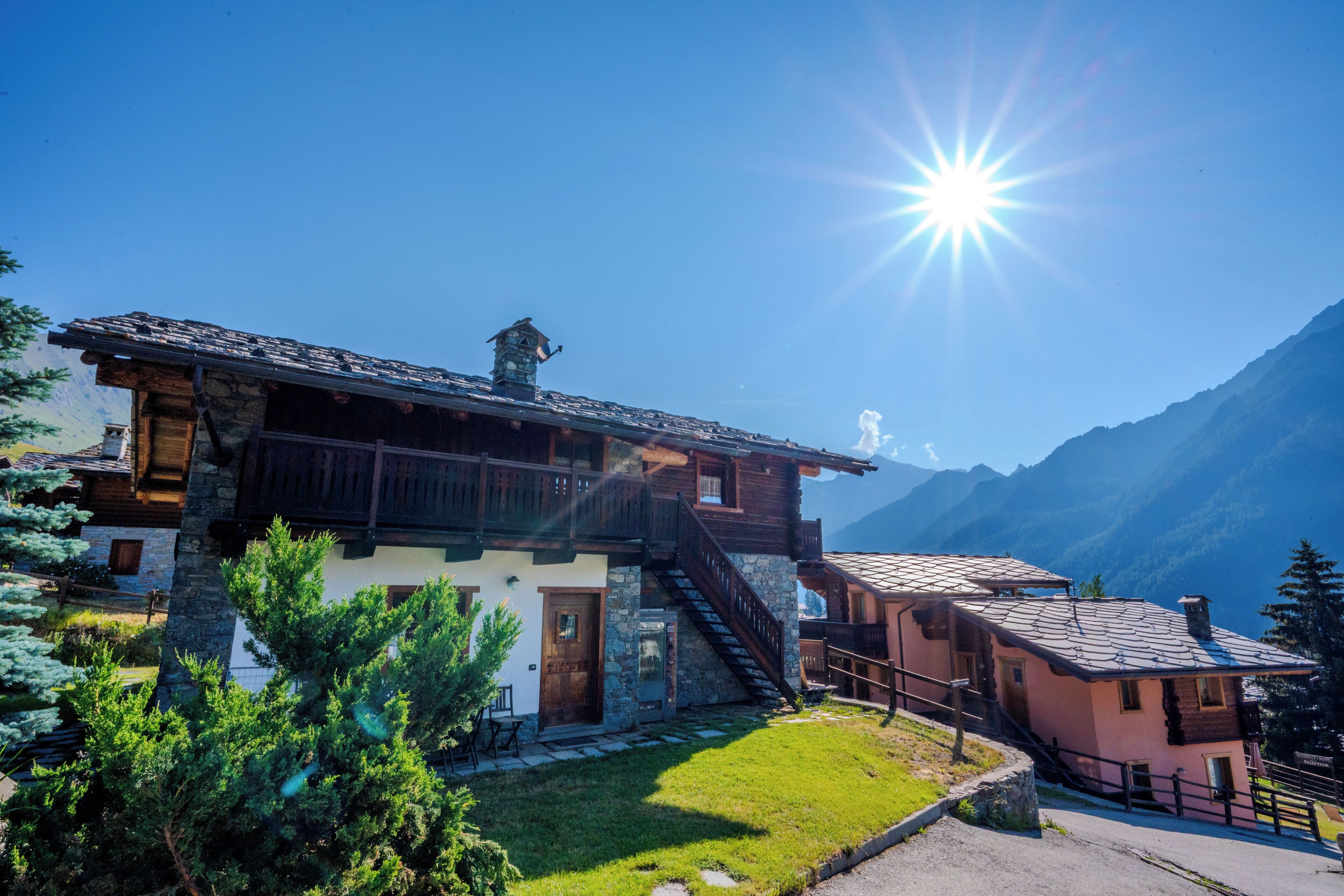 A traditional chalet with a stone facade, wooden balconies, and a staircase leading to the entrance.