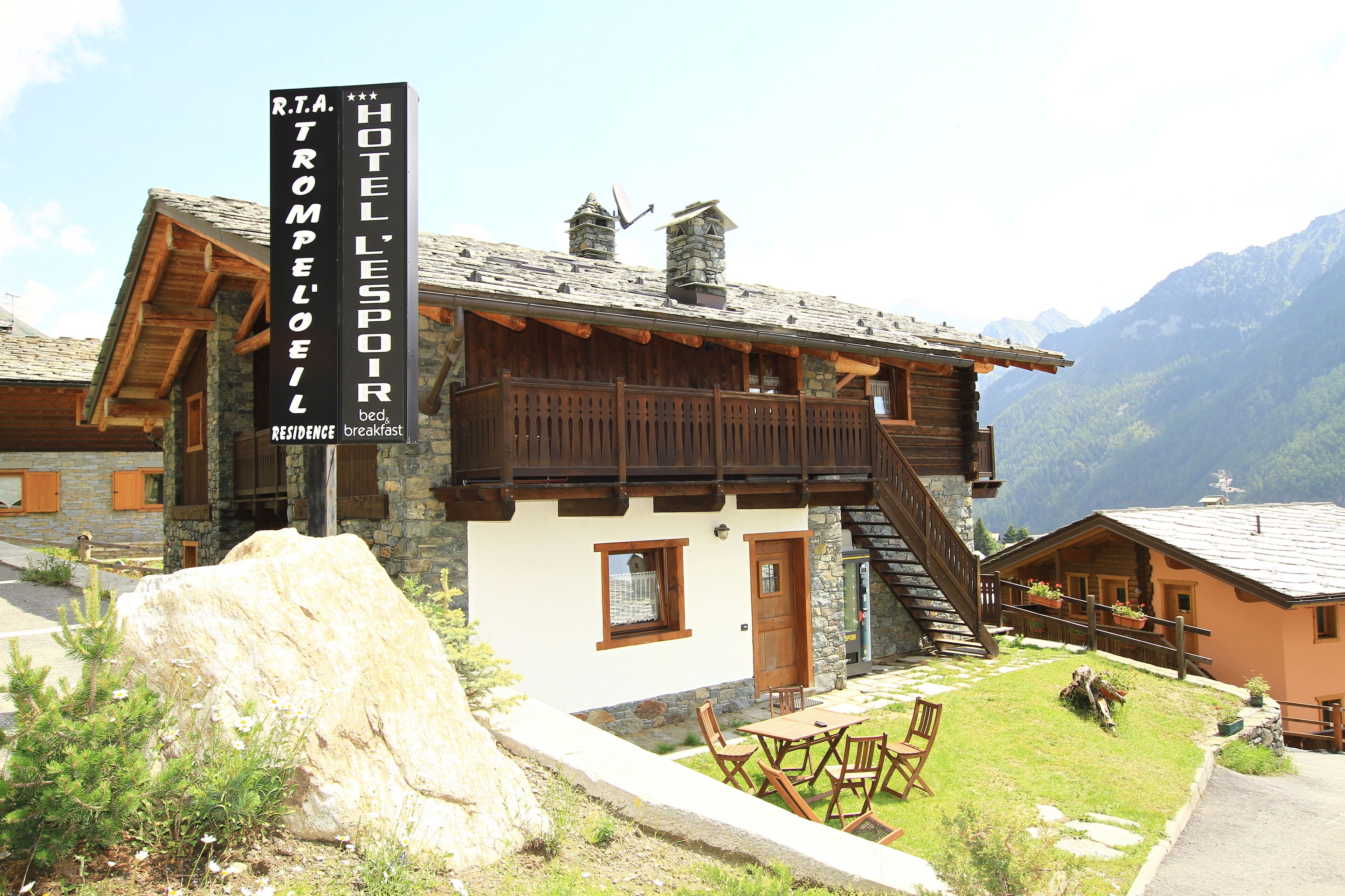 A mountain lodge with a stone facade, wooden balconies, and a stone chimney.