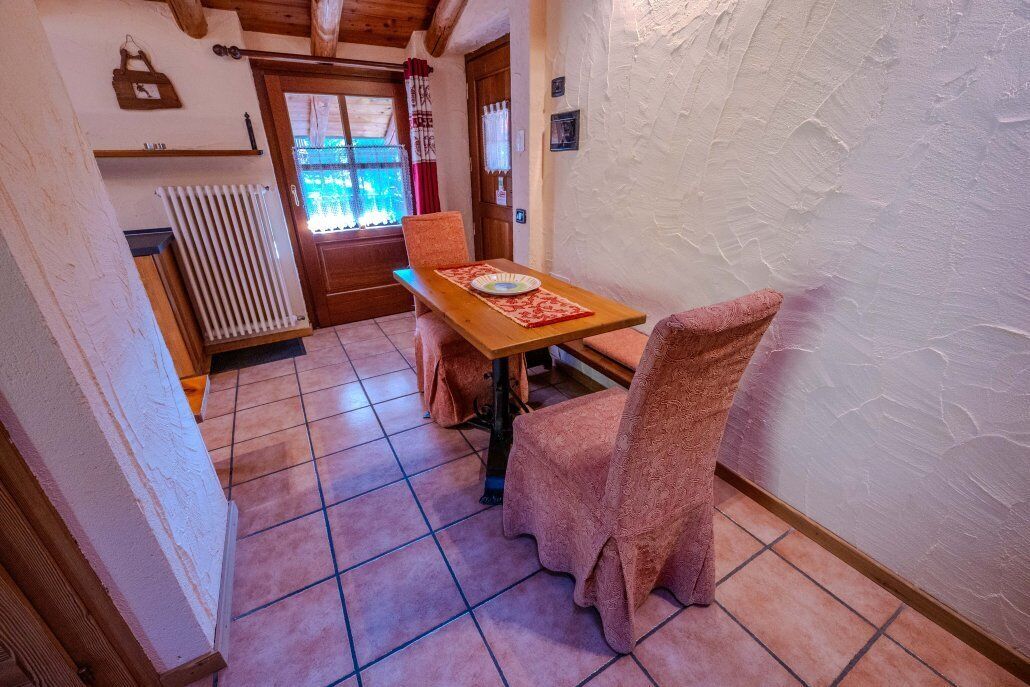 A cozy room with a wooden table, two chairs, a radiator, and a door leading outside.