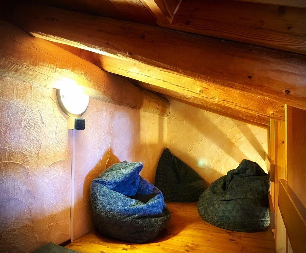 A cozy attic room with a sloped ceiling, a wall-mounted light, and two bean bags.