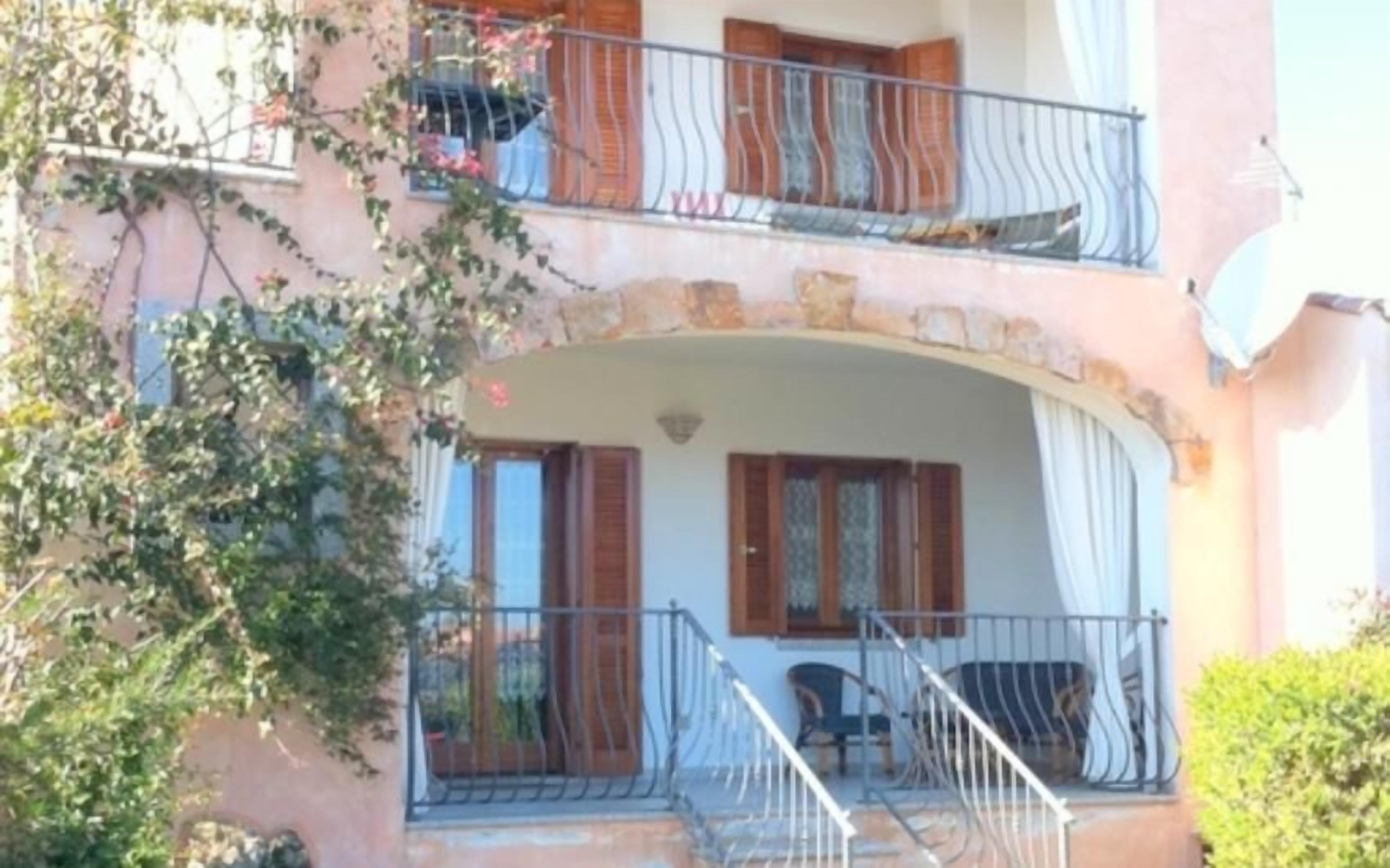 Un bâtiment à deux étages doté d’un balcon, d’un escalier et d’une porte.