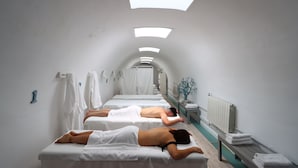 Een spa-ruimte met twee massagetafels, een radiator en een bank met handdoeken.