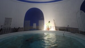 Een binnenzwembad met een hoge plafond en blauwe decoratieve elementen.