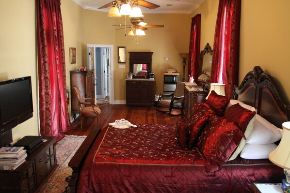 A bedroom with a large bed, a television, a desk, and a ceiling fan. - Rising Sun Bed & Breakfast (Natchez)
