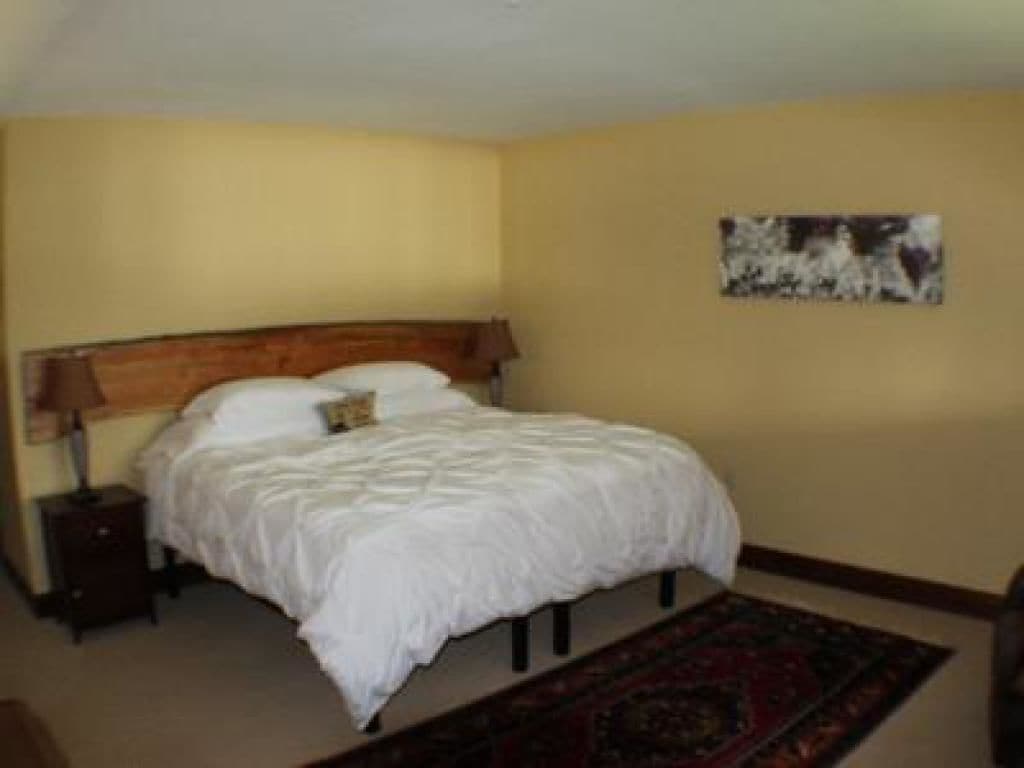 A bedroom with a bed, nightstand, and a painting on the wall.
