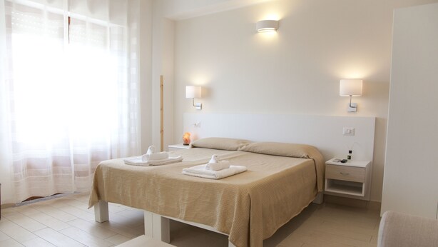 Une chambre d’hôtel comprenant un lit, des tables de chevet, une petite table et une chaise.
