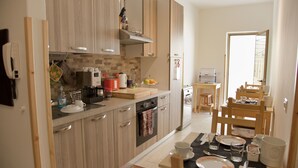 Une cuisine moderne avec des meubles en bois, un four encastré et un coin repas avec une table dressée pour deux personnes.