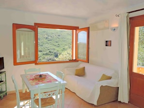 Relax in this inviting room with a sofa, table, and stunning view of the lush landscape.