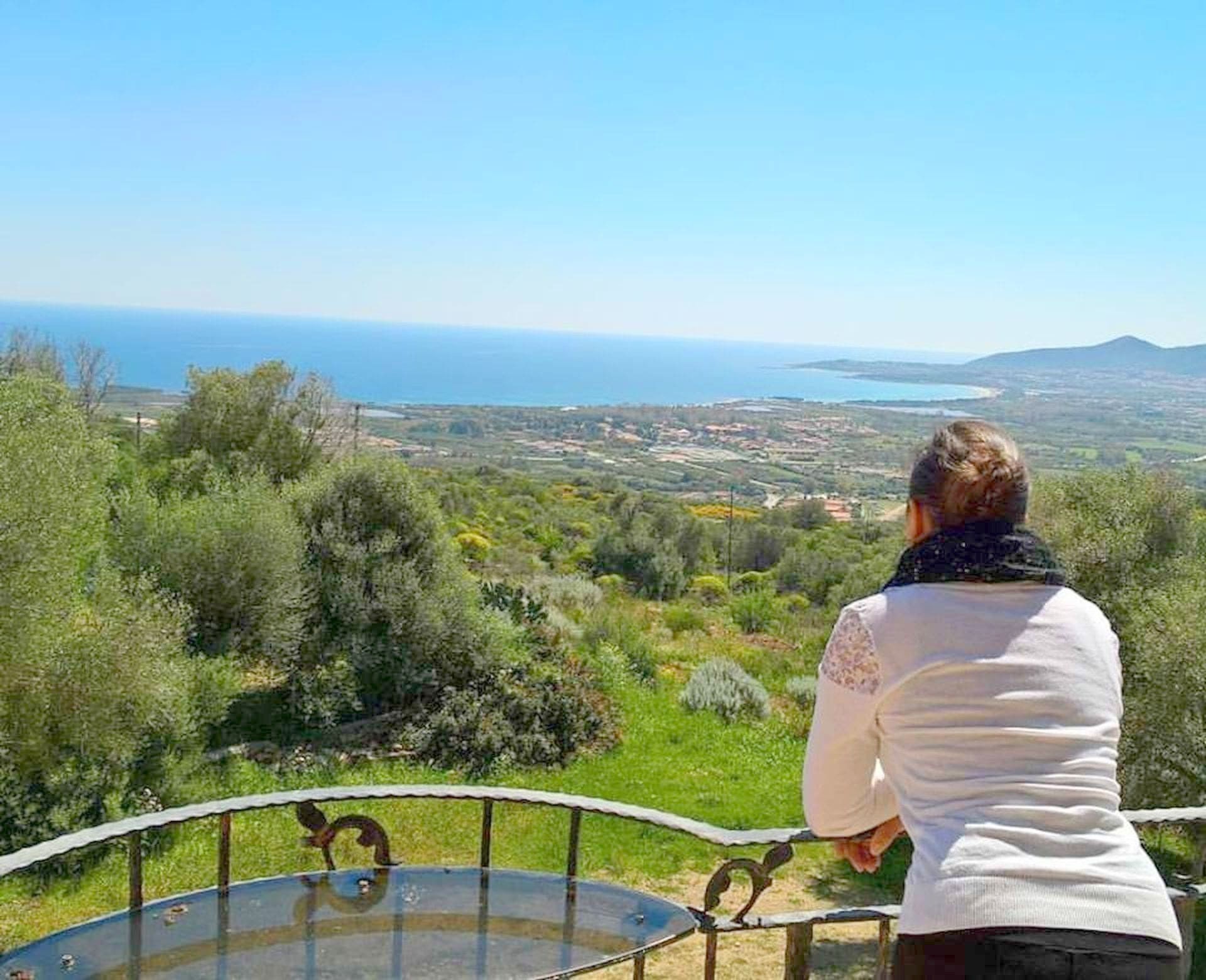 Une personne se tenant à un point de vue dominant un paysage magnifique, avec une vue sur la mer et les collines.