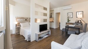 Un espace de vie moderne, à aire ouverte, comprenant un téléviseur, un coin salon et une cuisine.