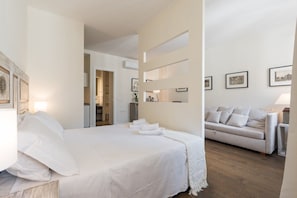 A hotel room with a bed, a sofa, and a wall with framed pictures.