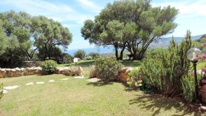A garden with stone walls, a lamp post, and trees. - Villa Ludduì L2 (Budoni)