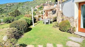 A house with a stone exterior, a small lawn, and a patio with a table and chairs. - Villa Ludduì L2 (Budoni)