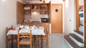 A compact kitchen with wooden cabinets, a gas stove, and a tiled backsplash. - The Muse (Massa Lubrense)