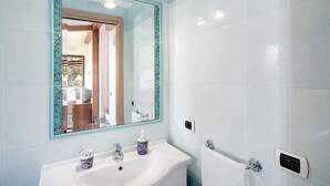 A bathroom with a white sink, a mirror with a decorative frame, and a toilet. - The Muse (Massa Lubrense)