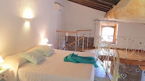 A bedroom with a bed, pillows, a nightstand, a window, and a staircase. - Villa Ludduì L (Budoni)