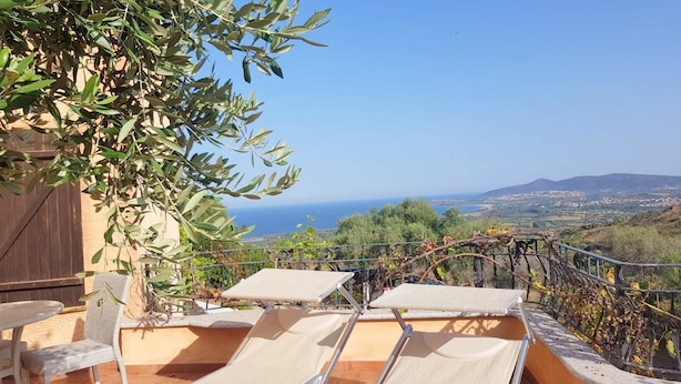 A terrace with two sun loungers, a pergola, and a view of the sea and landscape. - Villa Ludduì L (Budoni)