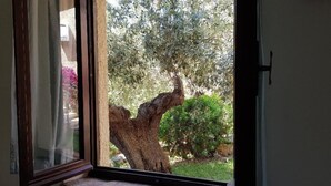 A window with a stone ledge, overlooking a tree and greenery. - Villa Ludduì L (Budoni)