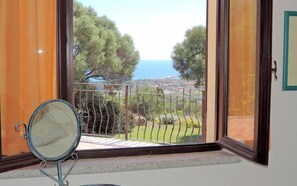 A balcony with a view of the sea and trees.