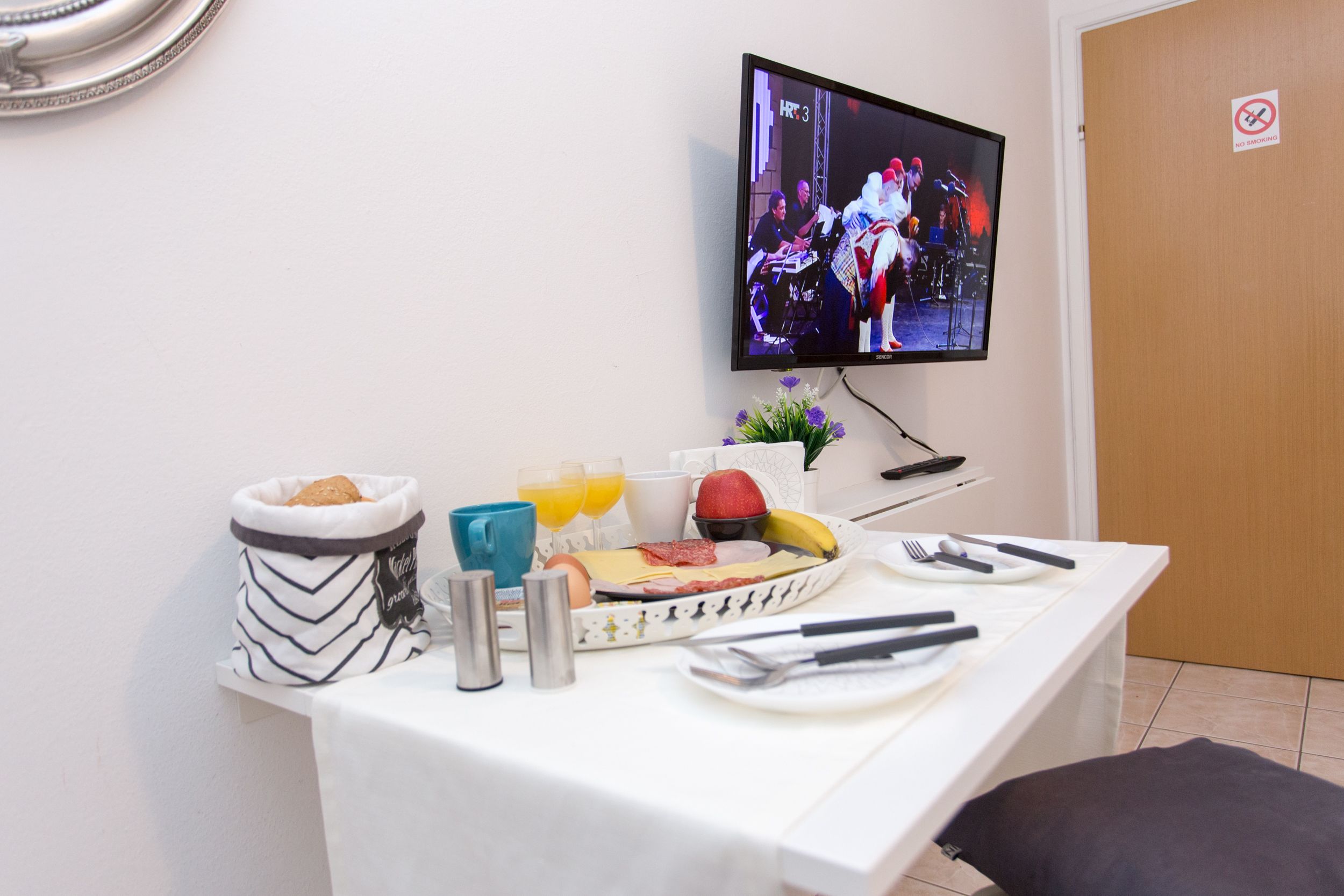 A breakfast setup with a TV displaying a live event, a tray with food and drinks, and a small plant.