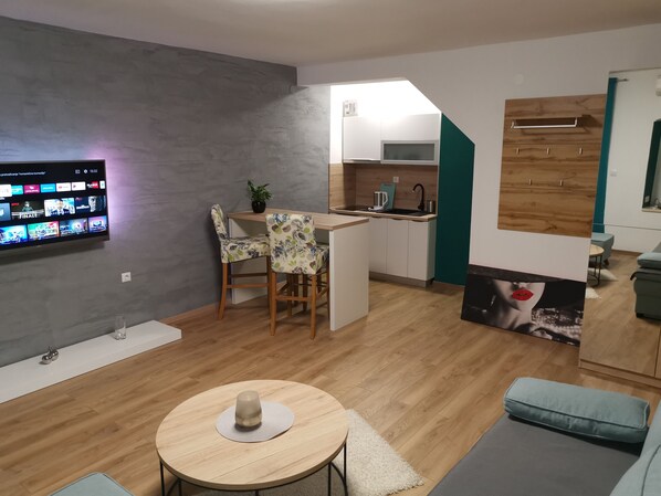 Un salon moderne doté d’un téléviseur à écran plat, d’un coin repas et d’une cuisine.